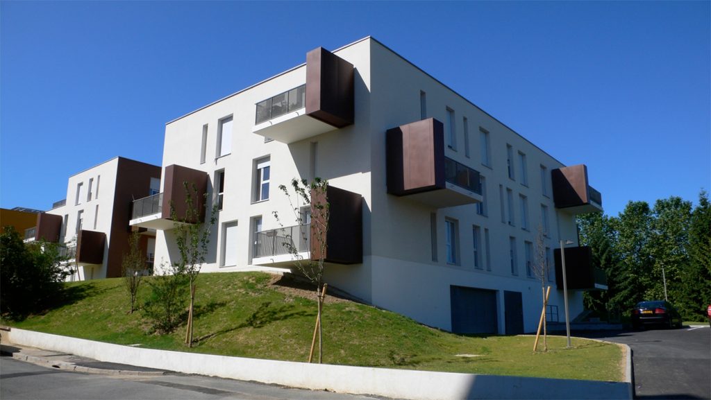 Un des trois immeubles du projet, aux façades blanches et balcons bruns.